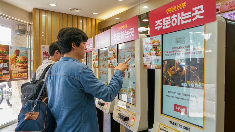 People placing orders at Korean Burger King kiosks