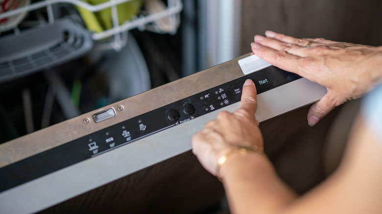 Close-up of female hand setting cycle on dishwasher
