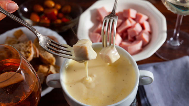 Close-up of forks dipping meat into cheese fondue