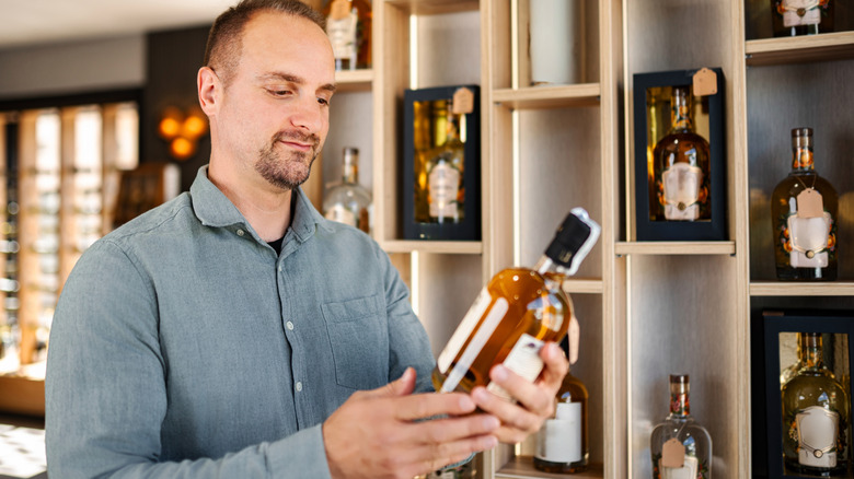 Customer looking at bottle of whiskey or bourbon in high-end store