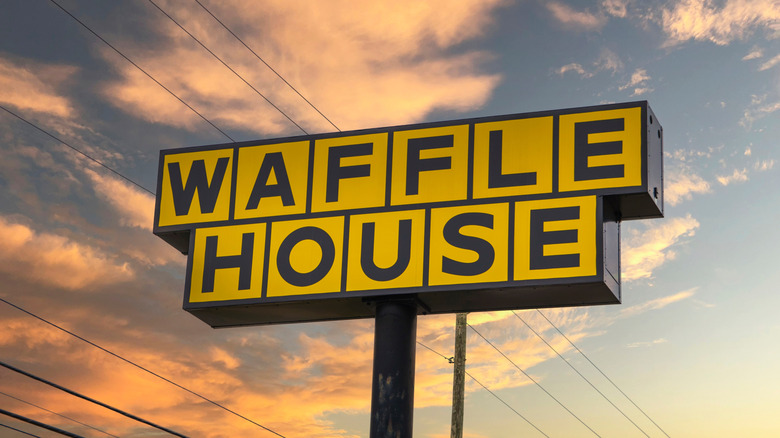 Yellow Waffle House sign against a pink sky