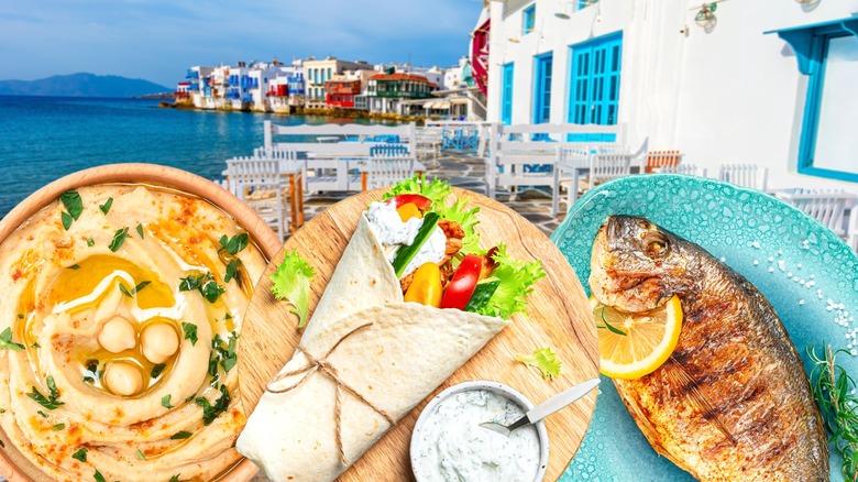 Hummus, a gyro, and a whole grilled fish on a Greek patio by the sea backdrop