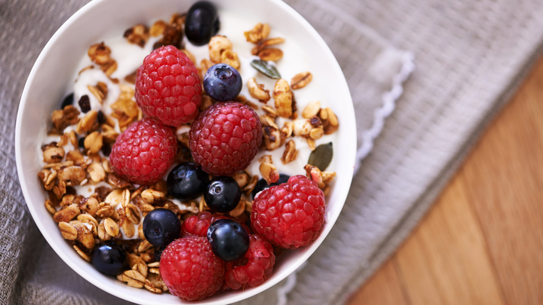 Overhead shot of yogurt bowl topped with granola, raspberries, and blueberries