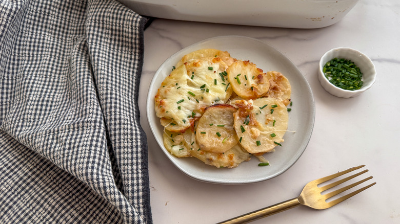 Cheesy potatoes on plate topped with chives