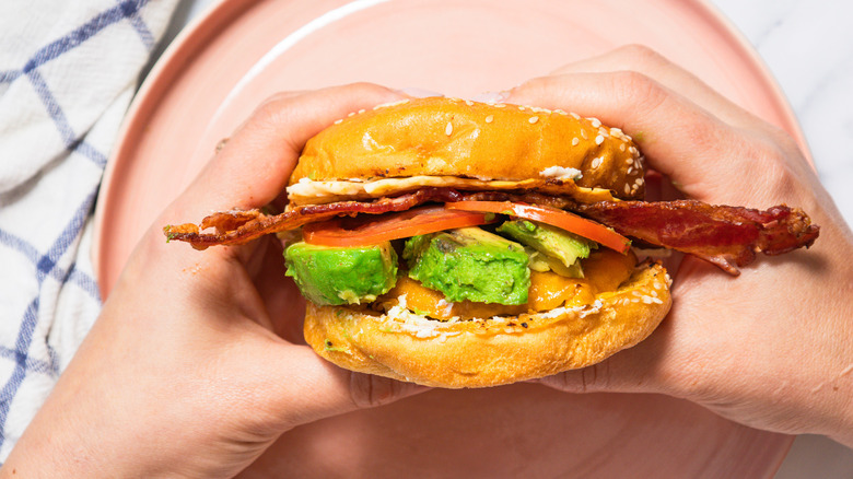 hands holding sausage breakfast burger