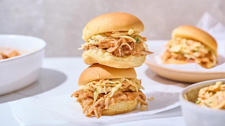 Slow Cooked BBQ Pulled Chicken Sliders stacked on parchment paper