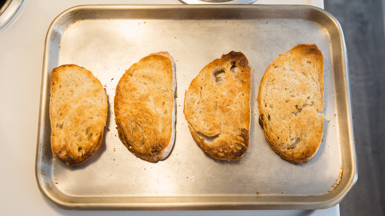 four slices of toasted bread on baking sheet