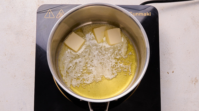 butter cubes melting in pool of oil in a saucepan