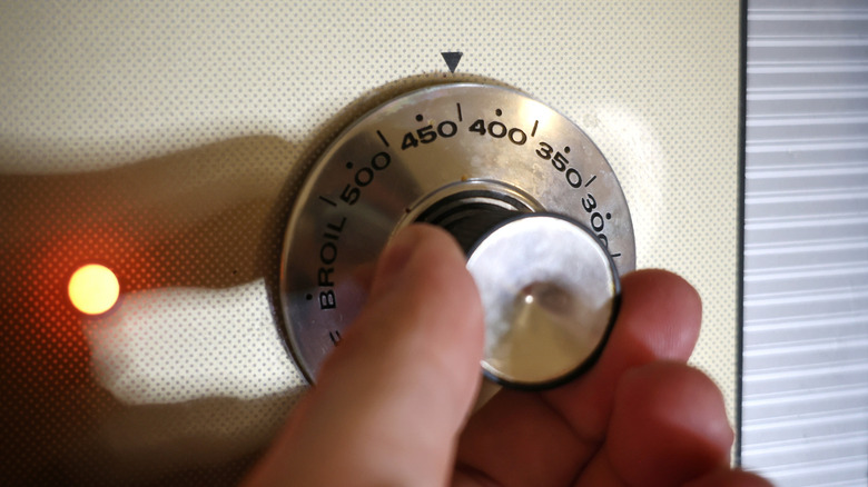 hand turning oven dial to 425 F
