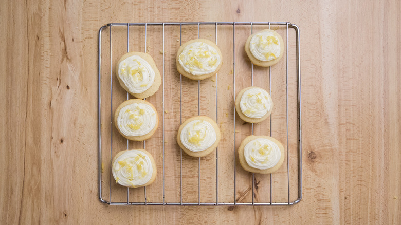 forested lemonade cookies with lemon zest on wire rack on top of wooden surface