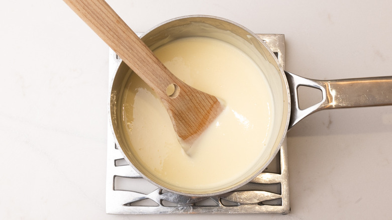 saucepan of hot custard with spatula inside resting on trivet