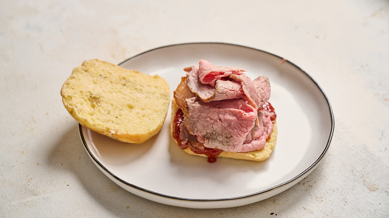 adding roast beef to onion roll