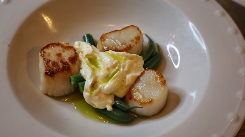 seared scallops and green beans plated with basil oil and orange ginger compound butter