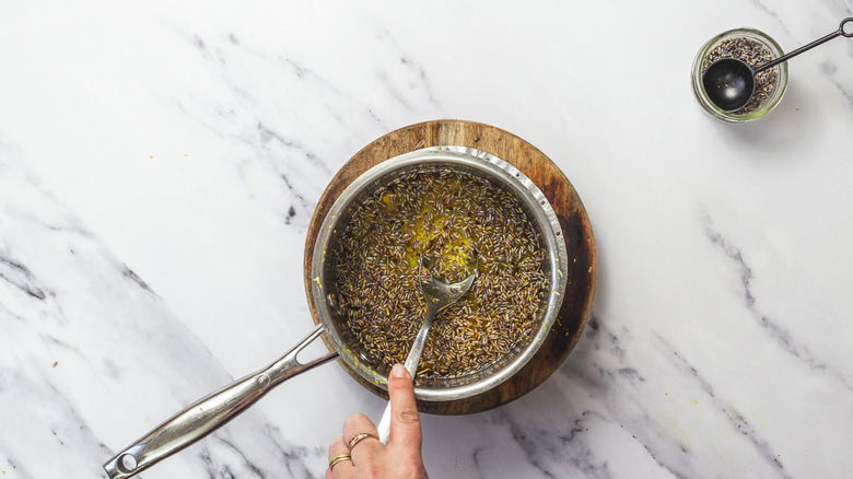 Mixing lavender buds in syrup in saucepan.