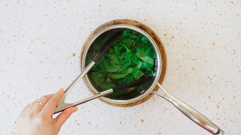 Blanching basil in pot of water
