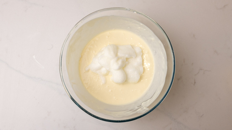 aerial view of egg white on top of custard mixture in glass bowl