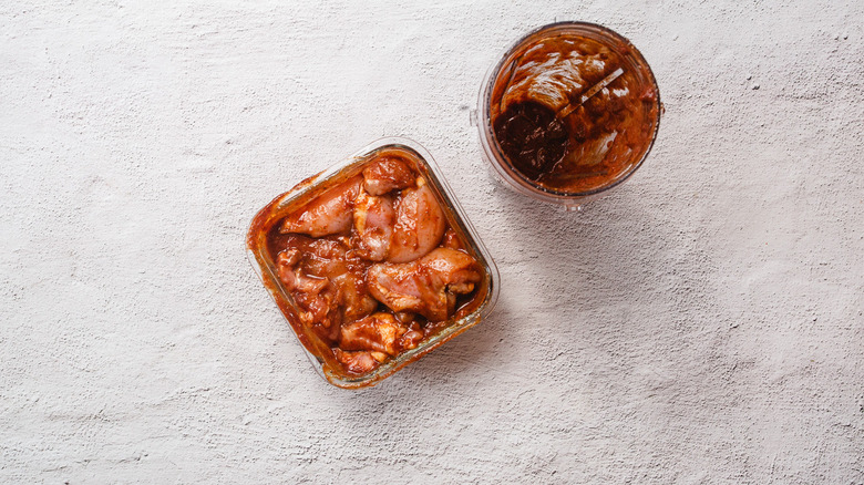 Container with marinade alongside container with chicken in marinade