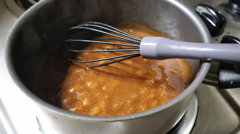 pot of simmering brown gravy with whisk in it