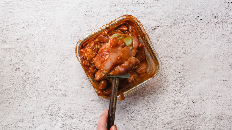 Lifting chicken from container with marinade