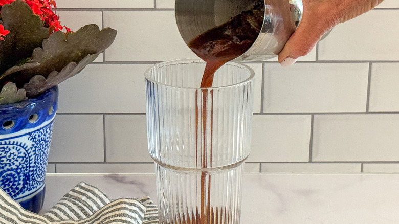 hand adding drink to glass