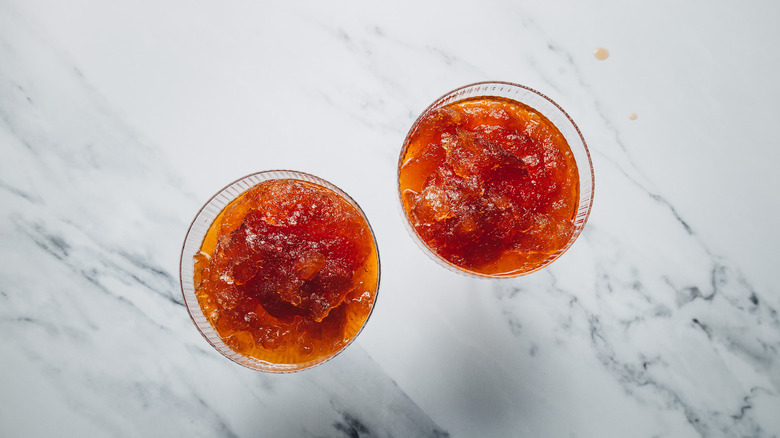 Two coupe glasses with the frozen mixture of a Manhattan cocktail.
