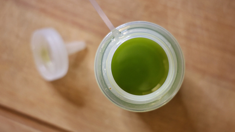 squeeze bottle of basil oil with top sitting beside it