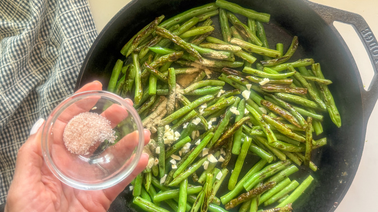 hand adding salt to pan