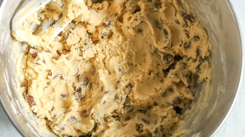 Chocolate chip cookie dough in stand mixer bowl with paddle attachment