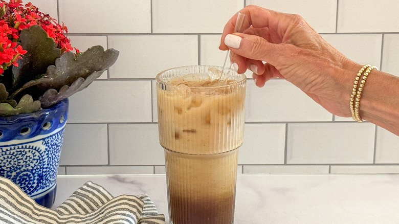 hand stirring drink with straw