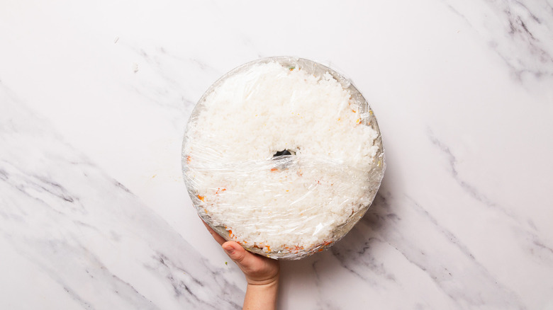 holding a plastic wrapped sushi bake