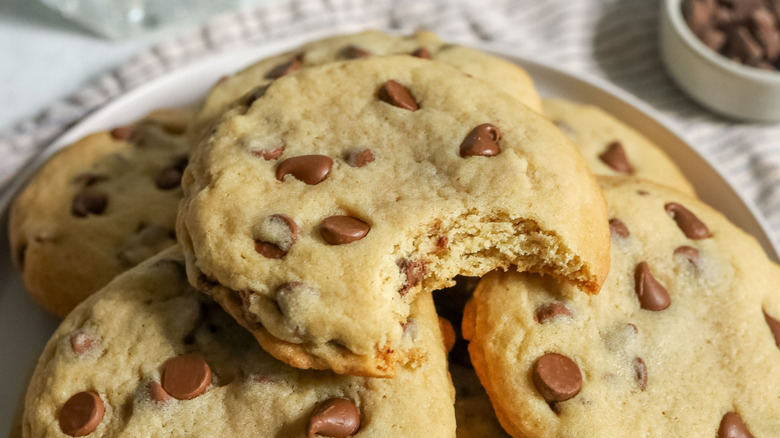 Chocolate chip cookie with bite taken stacked on top of more chocolate chip cookies