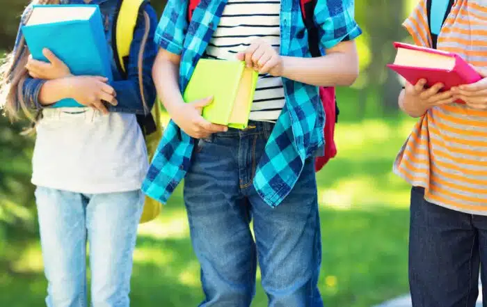 Pupils with books and backpacks walking in the park