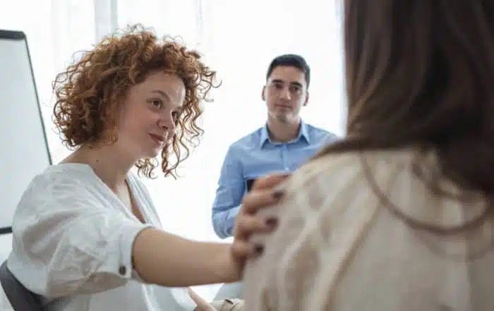 Support gesture. Woman comforting woman patient at group rehub meeting.