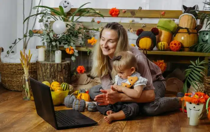 Holidays in the Time of COVID. Happy family, mother and baby celebrating Halloween via internet in new normal, Pandemic time. Online Holiday party concept.