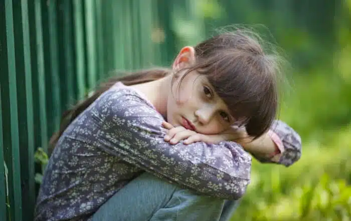 Lonely child with a sad expression in the yard