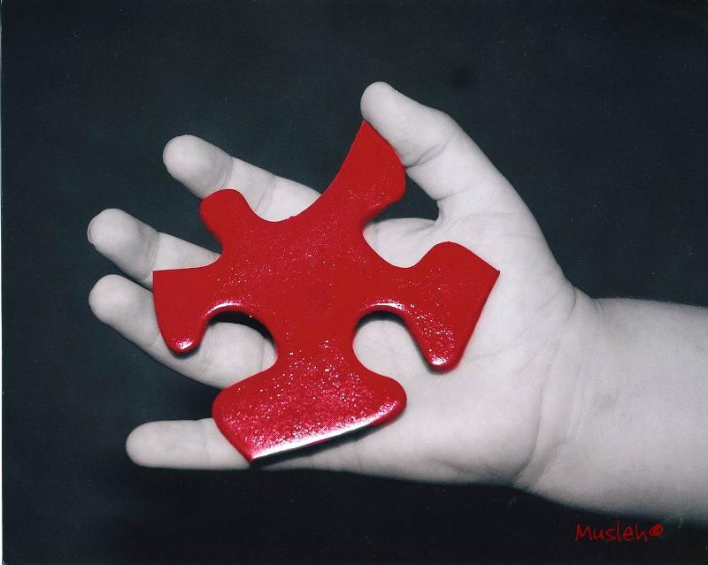 Close-up of a red puzzle piece being held in a hand