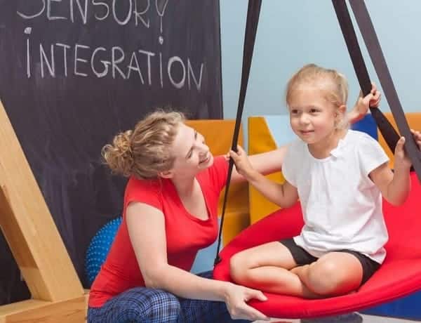 Woman helping a child play in a sensory integration space for therapy