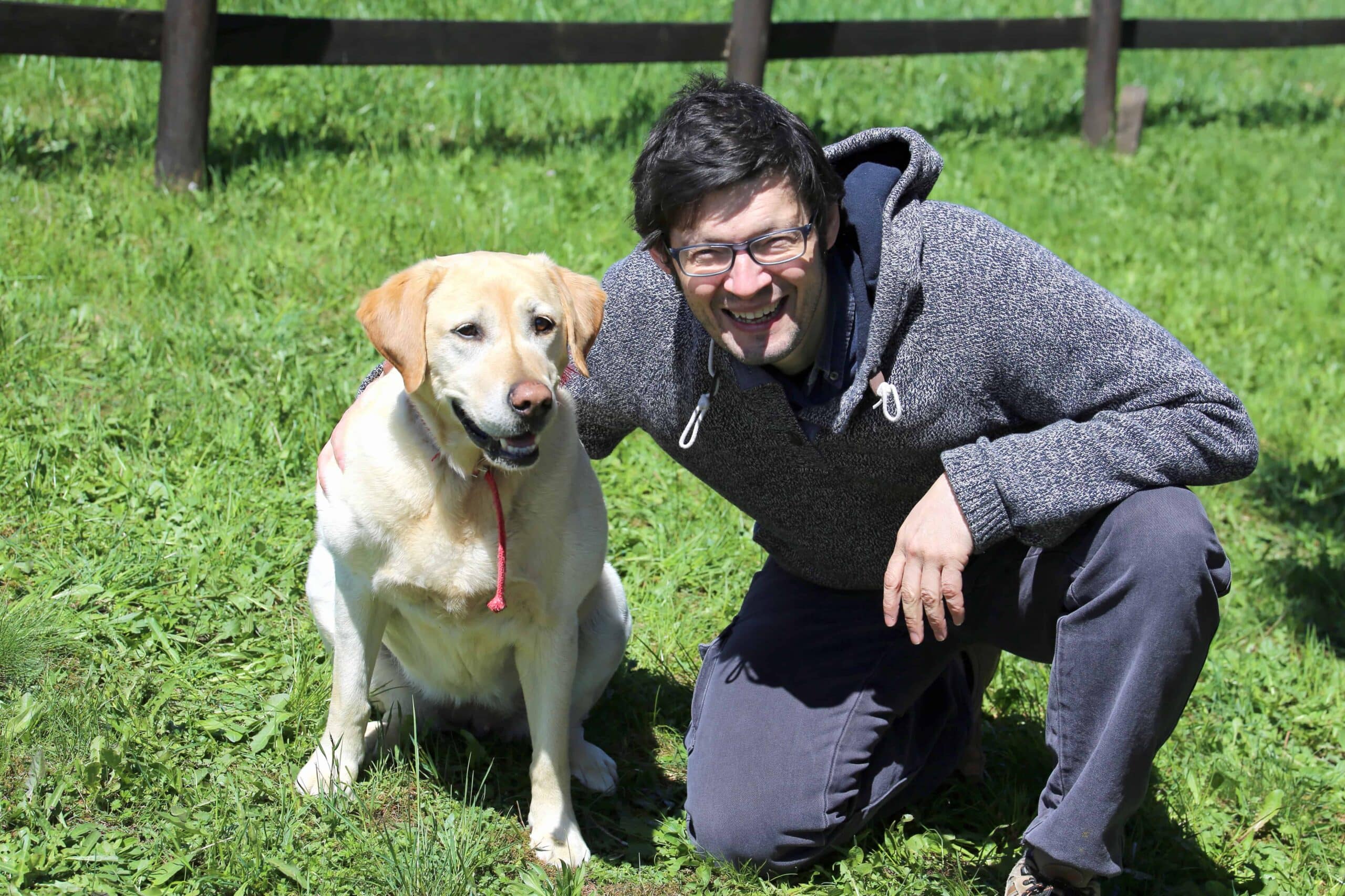 Young man with blacks hair smiling with his labrador dog