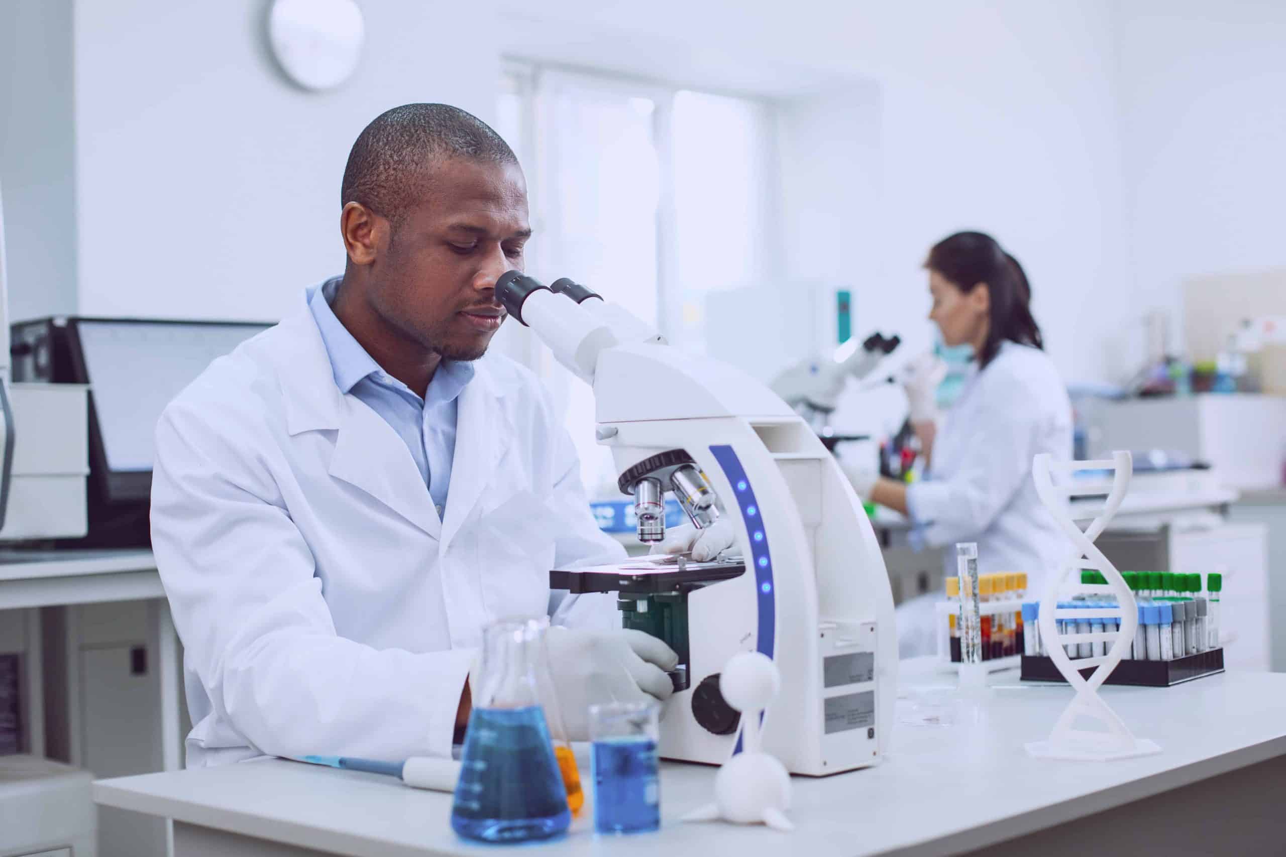 Serious male researcher working with his microscope