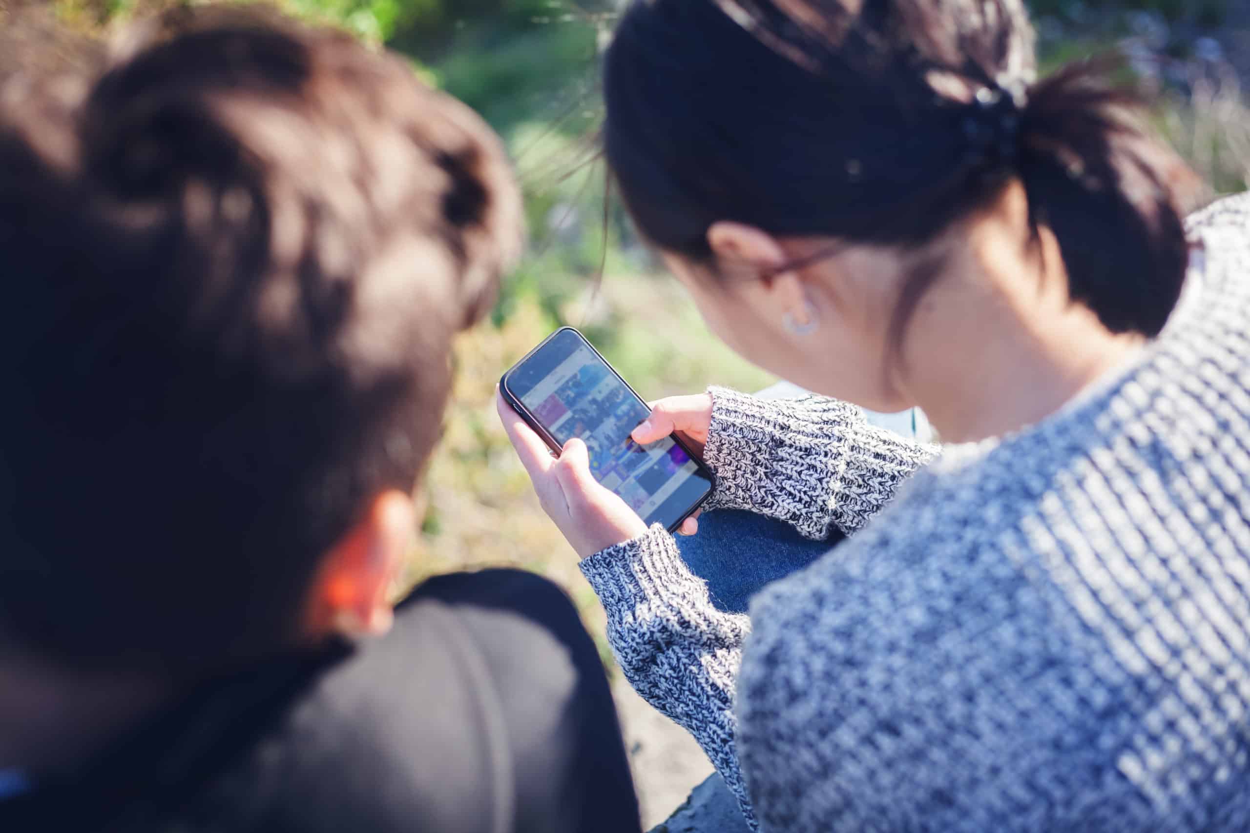 Asian teen boy and girl look in smartphone, communicate, have fun, millenial, teenagers rest together