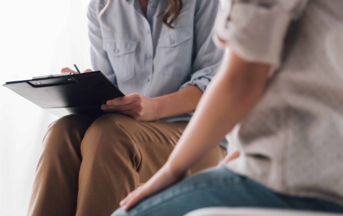 Cropped shot of psychologist with clipboard sitting in front of child