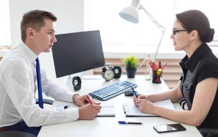 Young man and women having a conversation over a desk at work