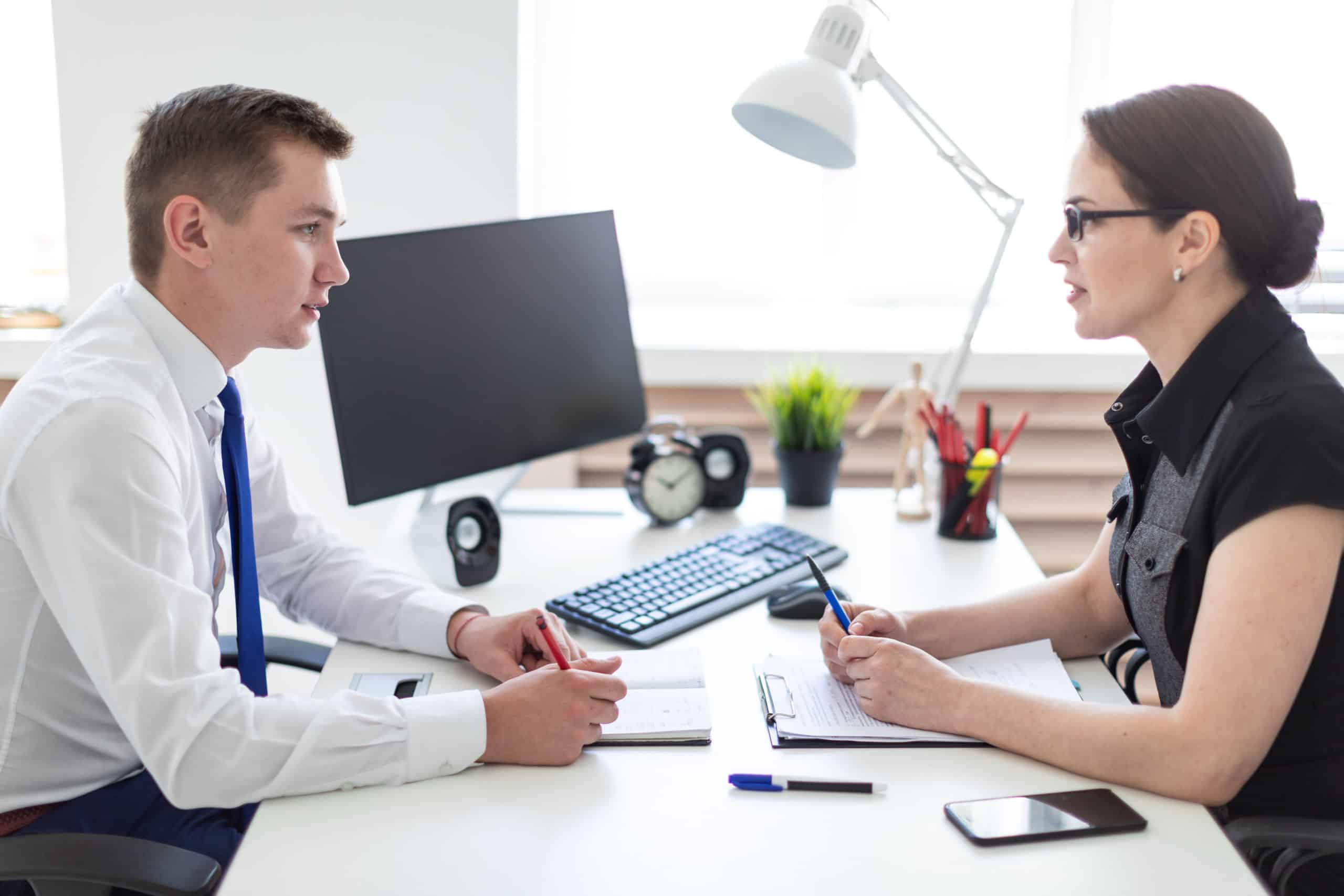 Young man and women having a conversation over a desk at work