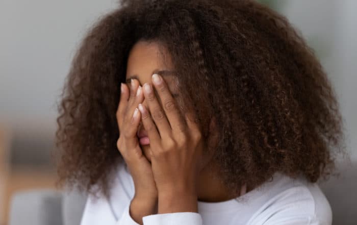 Anxious young girl covering her face