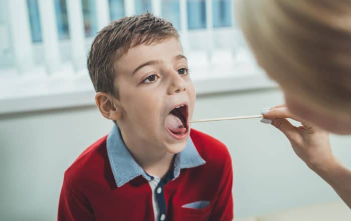 Boy has strep throat. Children's ENT doctor examines boy's throat. Children's diseases, medical examination.