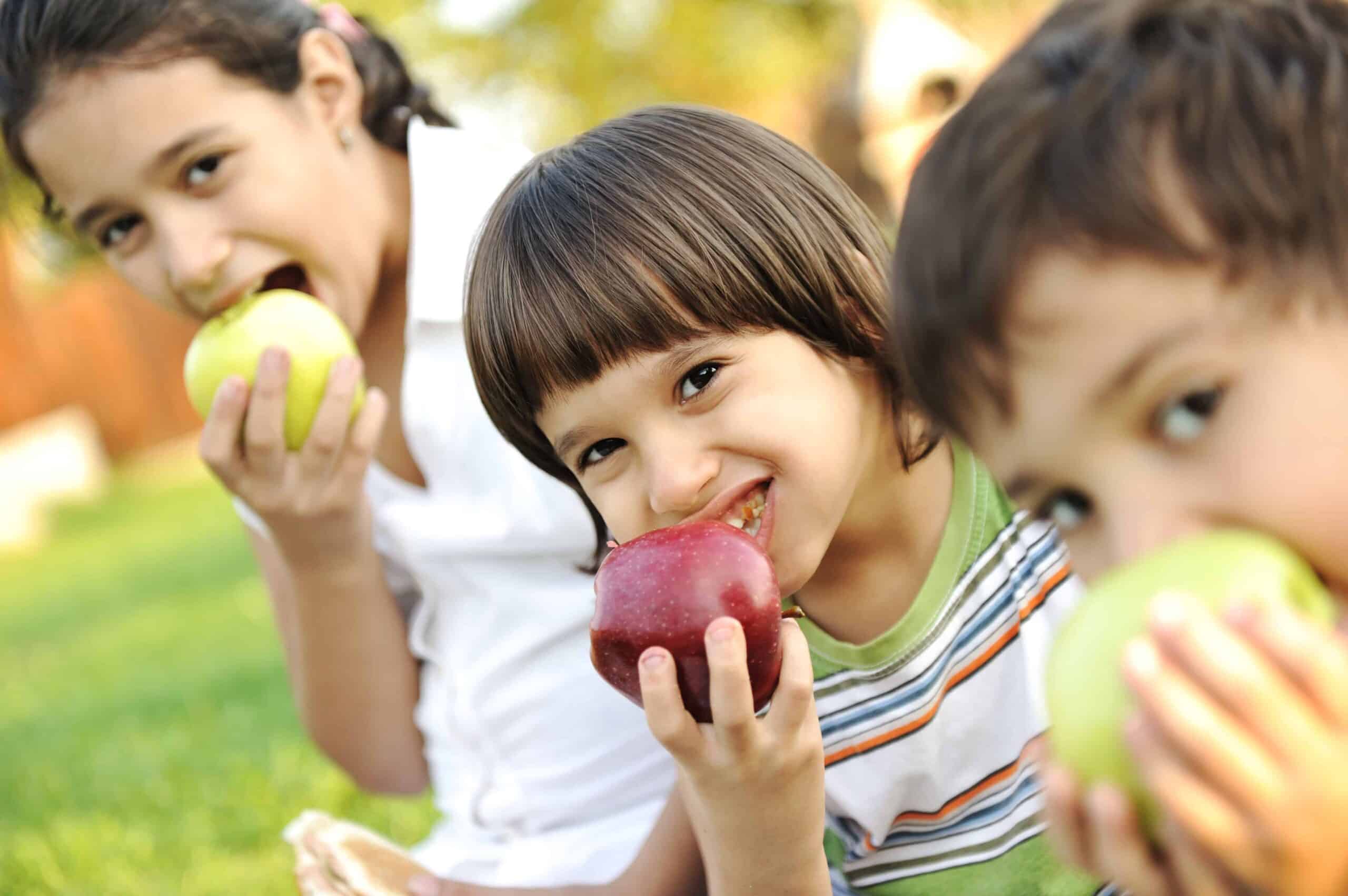 Three kids eating apples