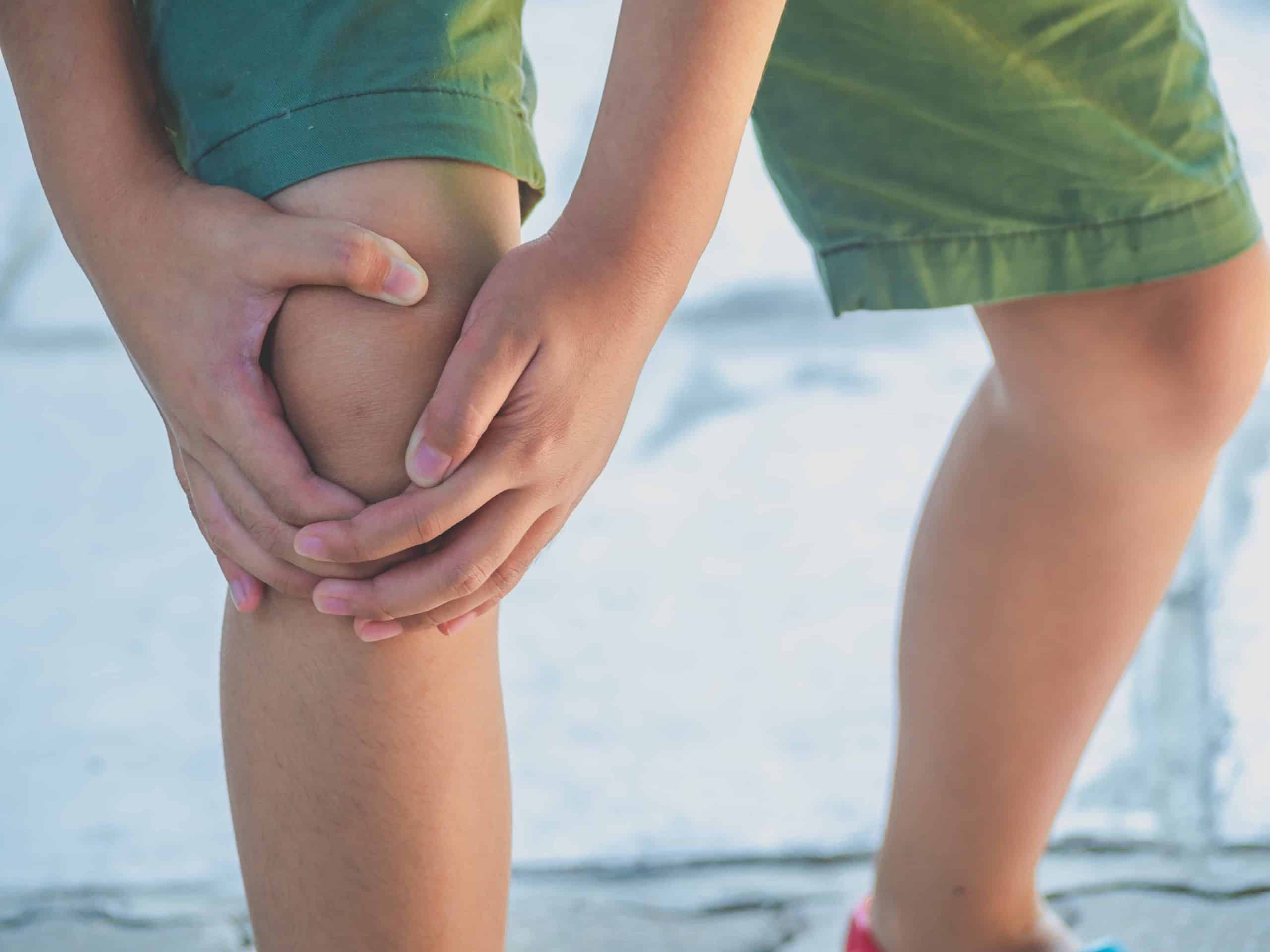 Kid with knee problems holding their knee