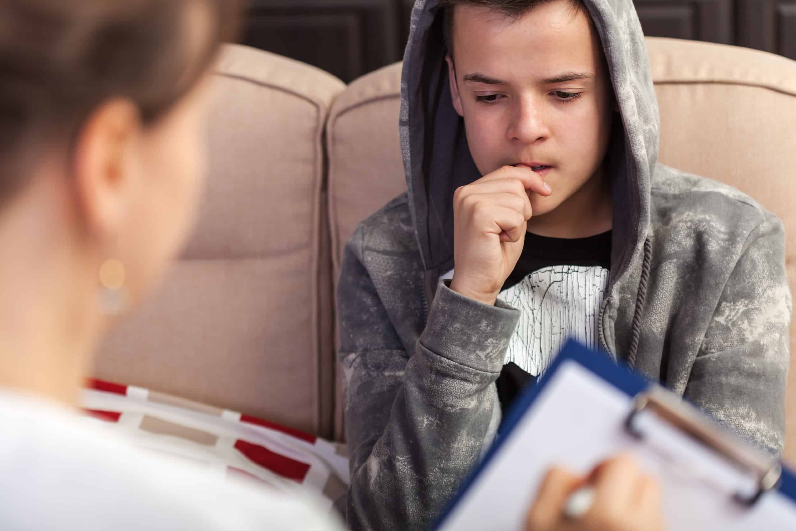 Boy with autism and depression seated in a doctor's office, lost in thought