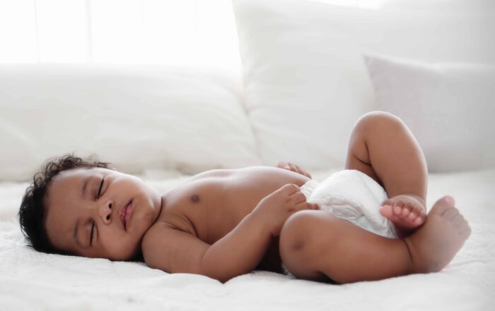 Close-up of a baby sleeping comfortably on a white bed