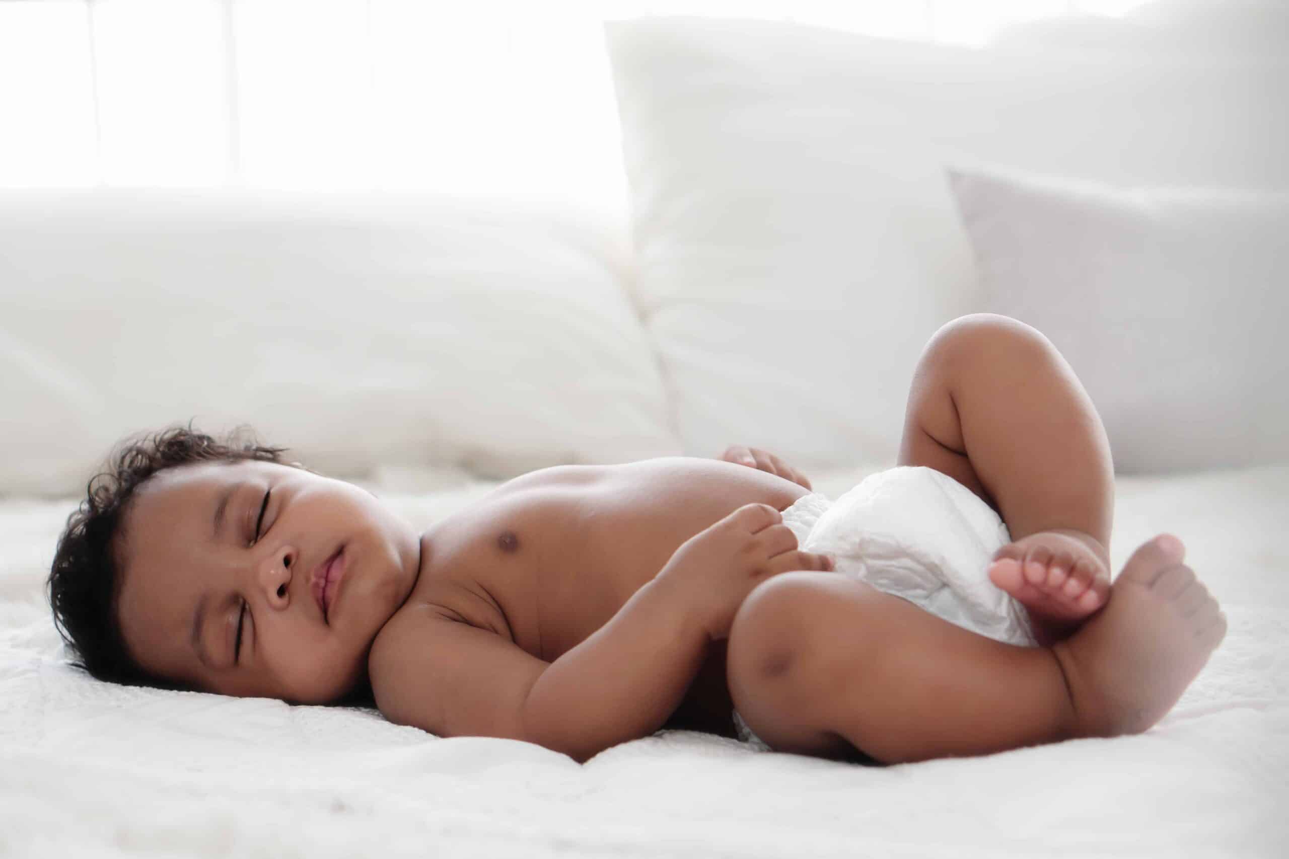 Close-up of a baby sleeping comfortably on a white bed